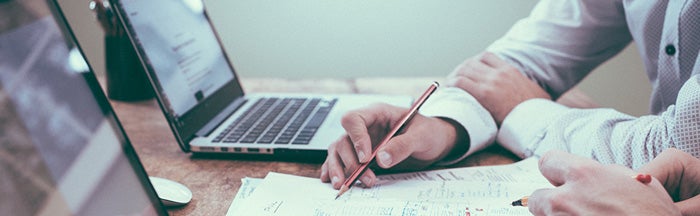 people working at a table on paper next to laptops